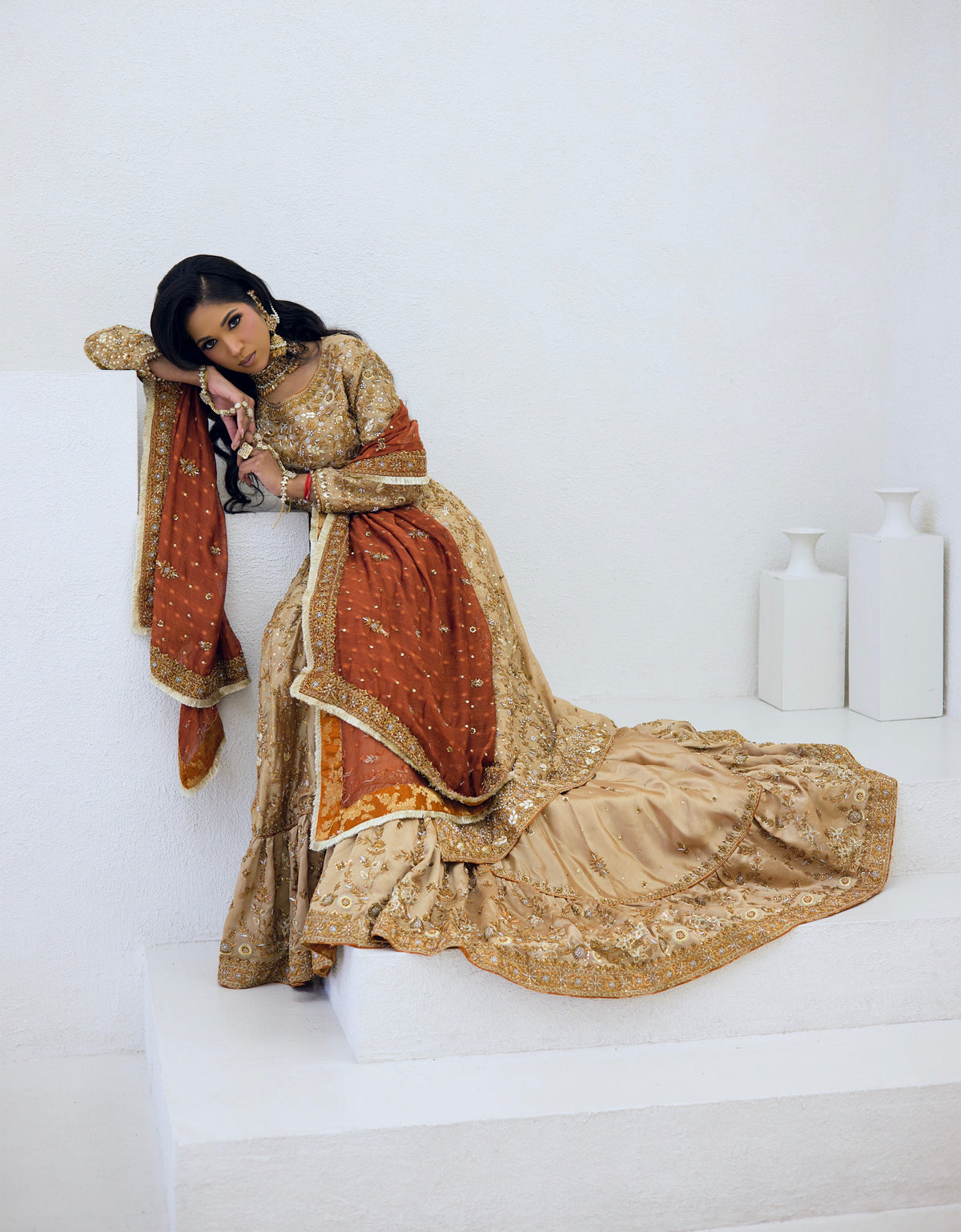 A warm heritage bridal atelier interior at golden hour, embroidery frames, fabric bolts in